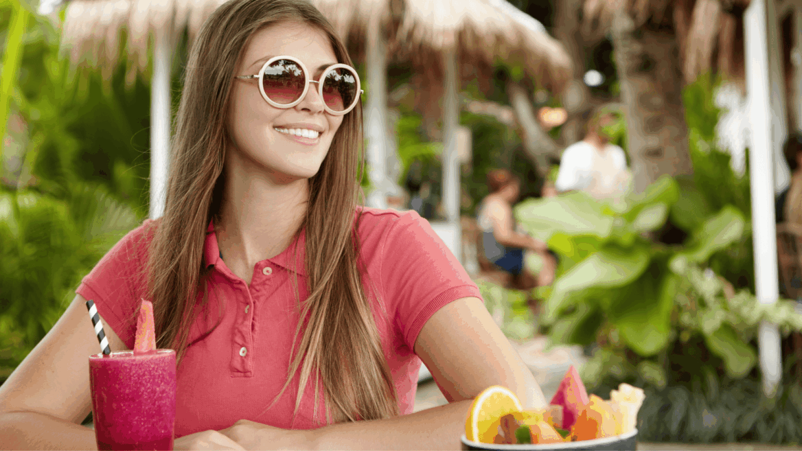mujer sonriente con smoothie tropical y frutas