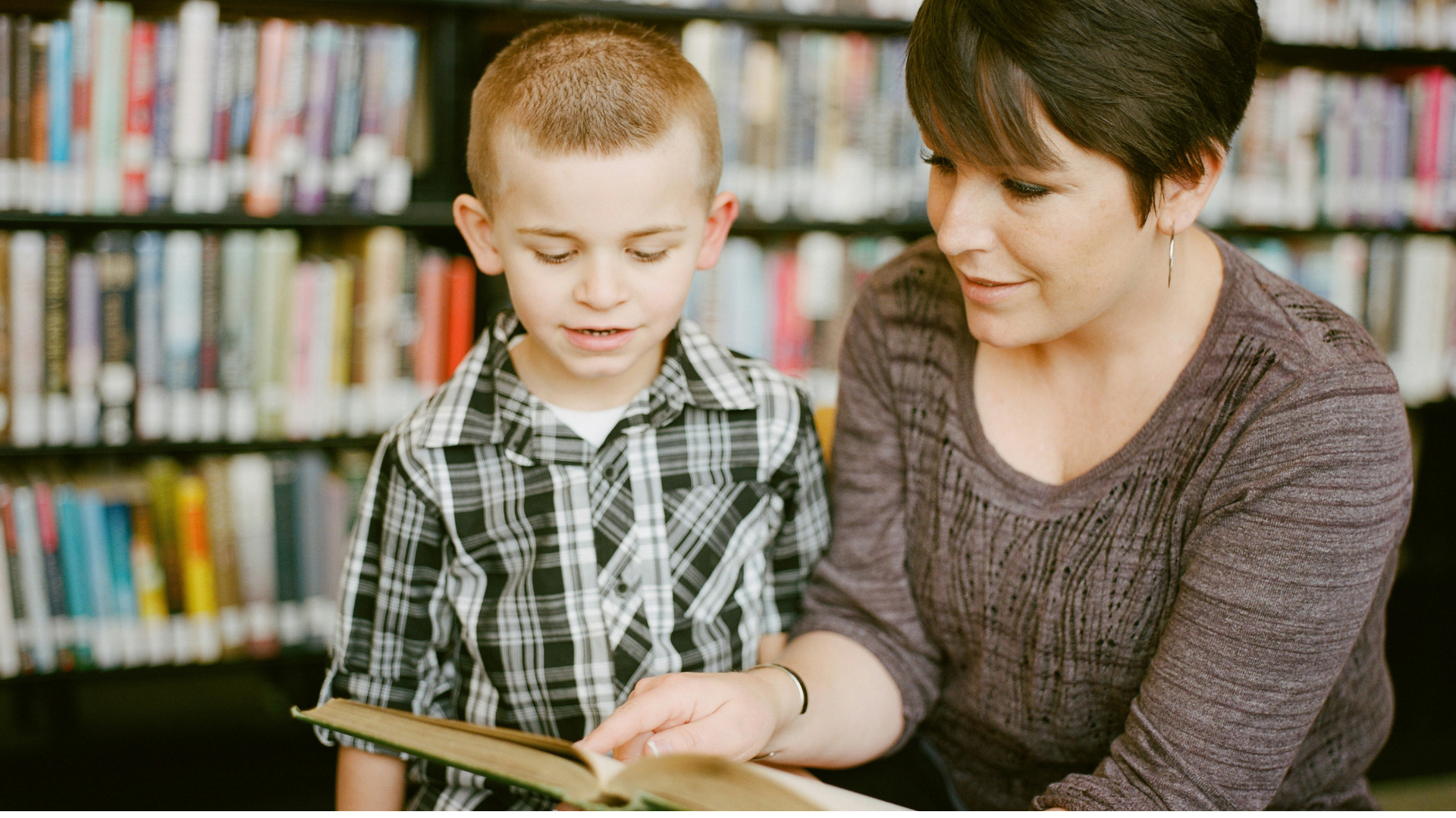 mutter und sohn lesen gemeinsam in der bibliothek