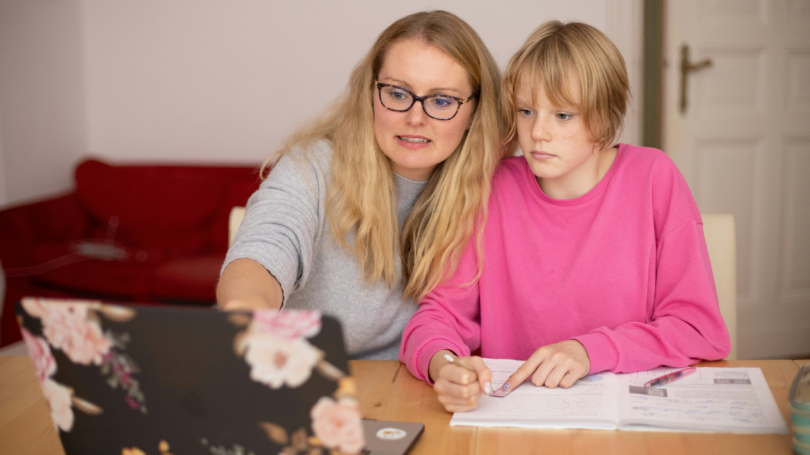 mutter hilft kind bei hausaufgaben am laptop