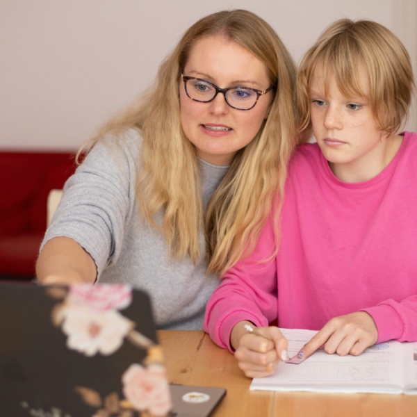 mutter hilft kind bei hausaufgaben am laptop