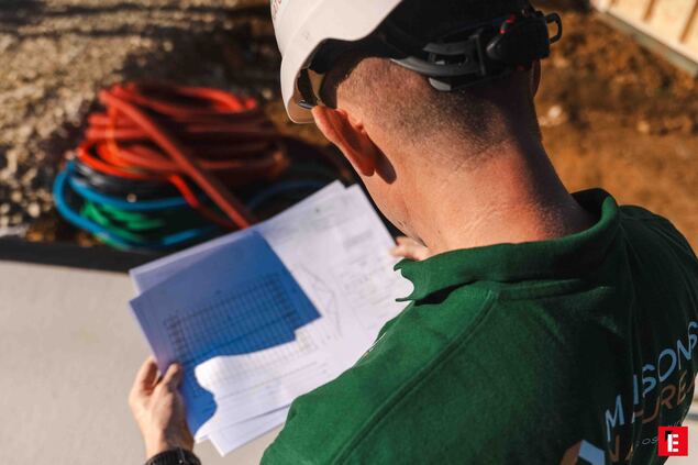 ouvrier casqué lisant des plans sur chantier