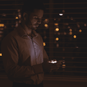 hombre con móvil junto a ventana nocturna