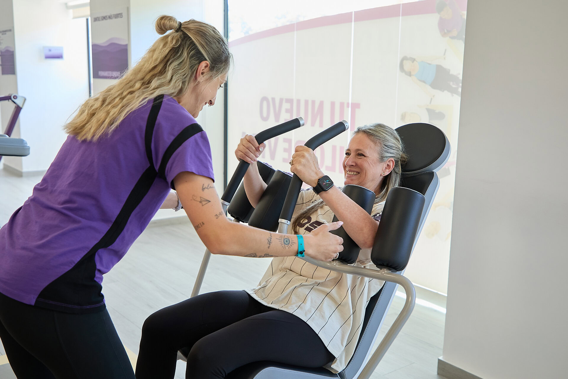 trainer aiuta donna senior su macchina fitness