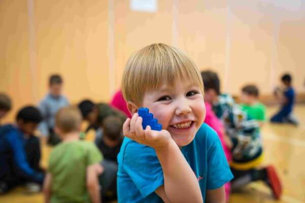 smiling preschool boy with blue block