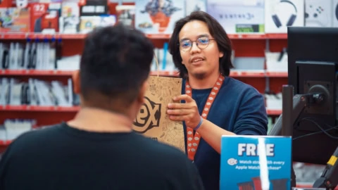 electronics store employee handing over shopping bag
