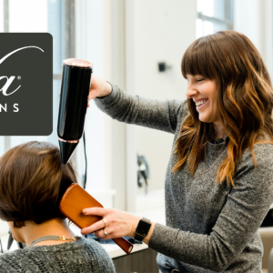 stylist blow drying client in light filled salon