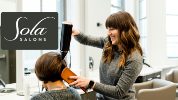 stylist blow drying client in light filled salon