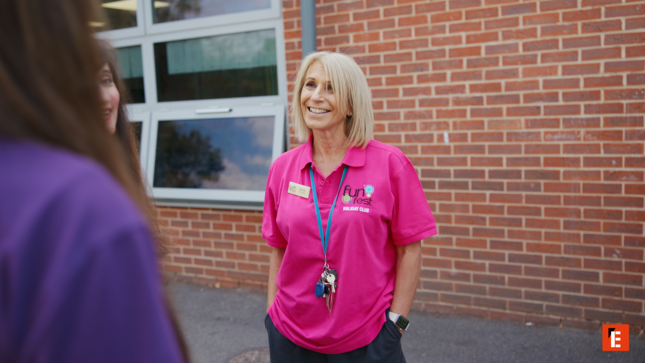 smiling woman in pink polo chats outdoors