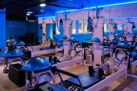 studio pilates moderne : réformers en bois et Éclairage bleu