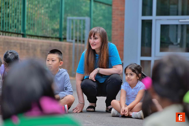 teacher leading outdoor group activity with children