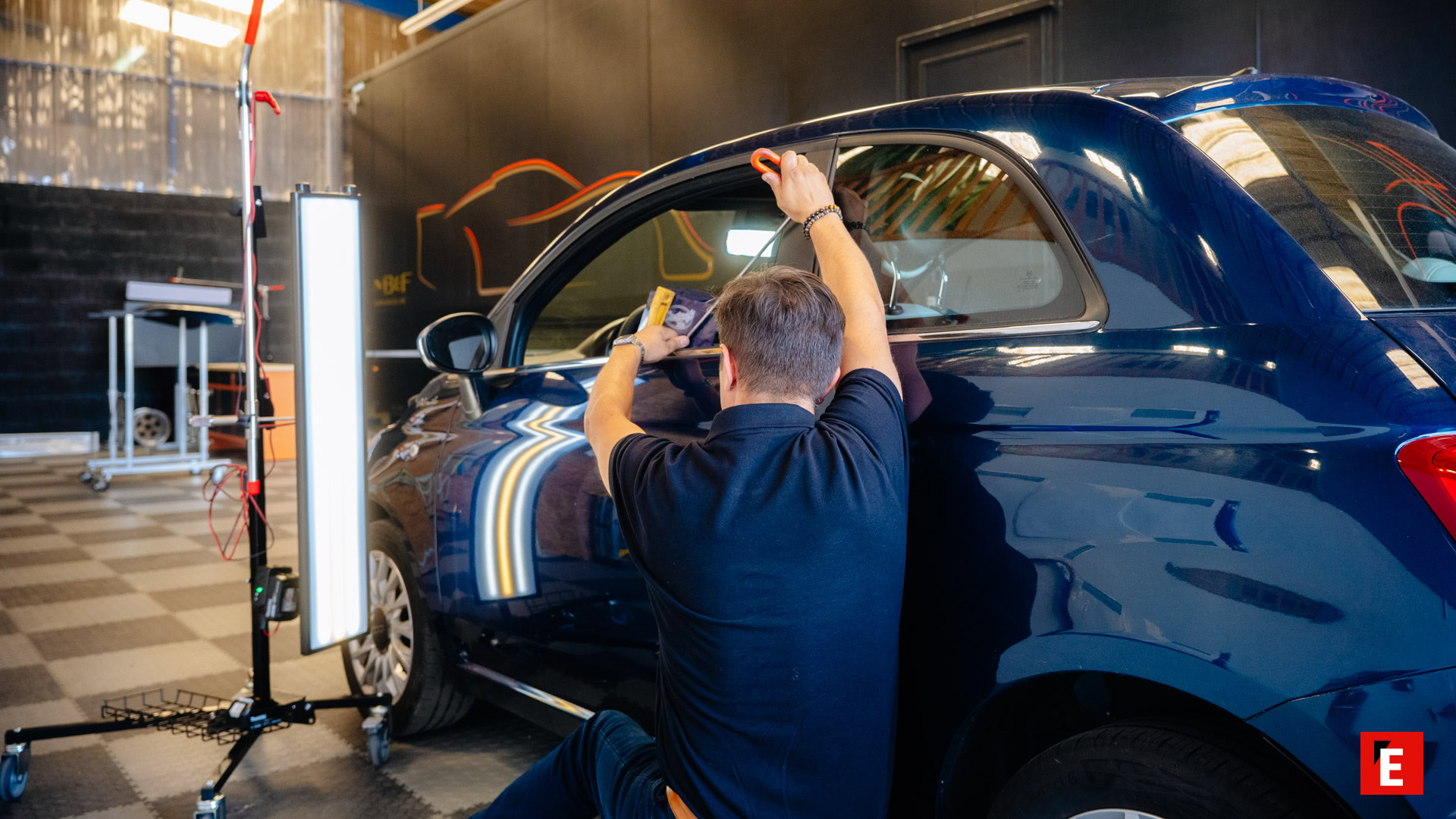 pose de film solaire sur voiture bleue en atelier