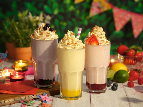 three frosty milkshakes with fresh berries
