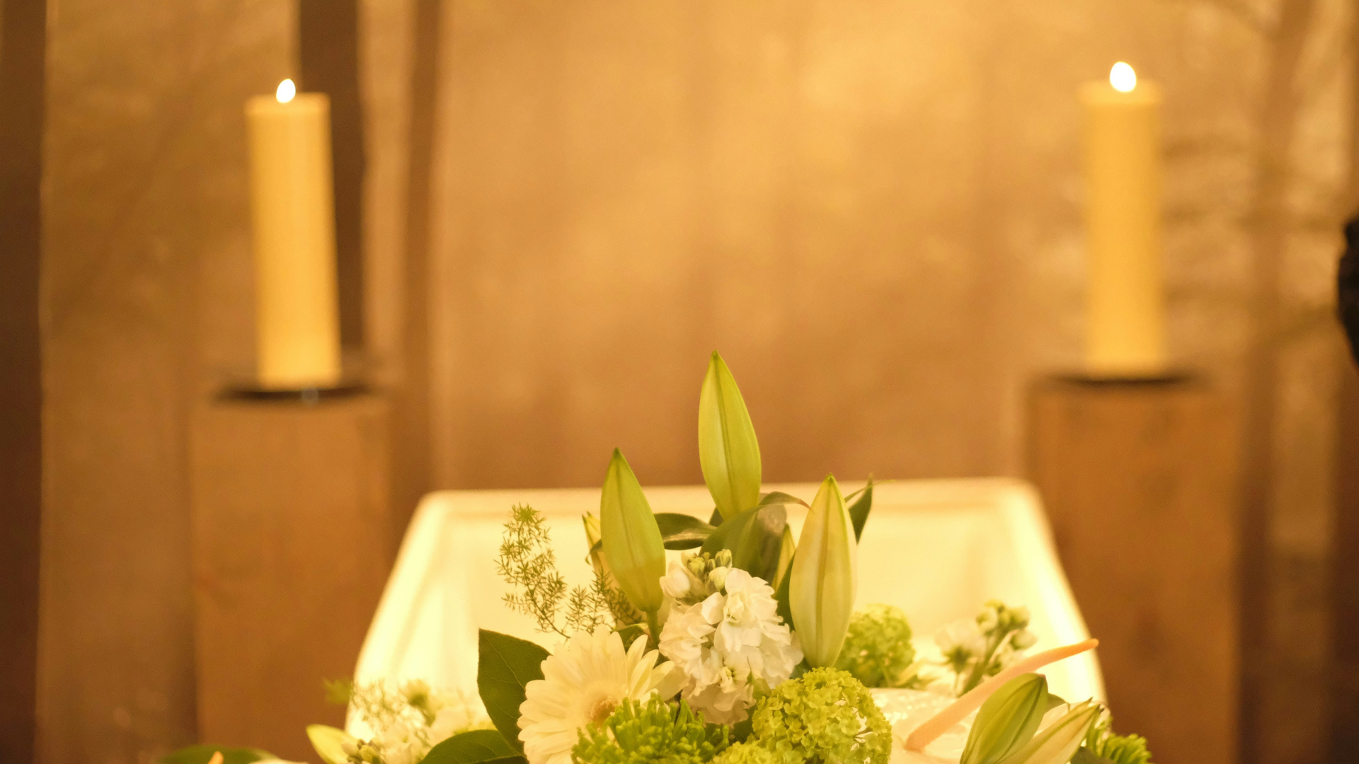 trauerblumen und kerzen im warmen licht