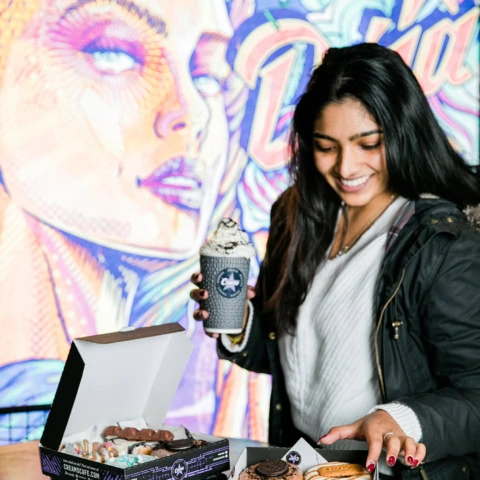 smiling woman with milkshake and colourful doughnuts