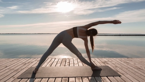 yoga al tramonto sul lago, donna in equilibrio