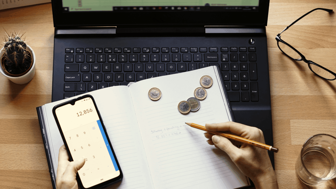 calculadora de presupuesto con portátil, libreta y monedas