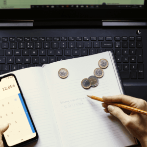 calculadora de presupuesto con portátil, libreta y monedas