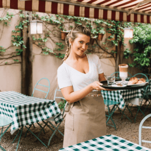 camarera sonriente con bandeja en terraza de café