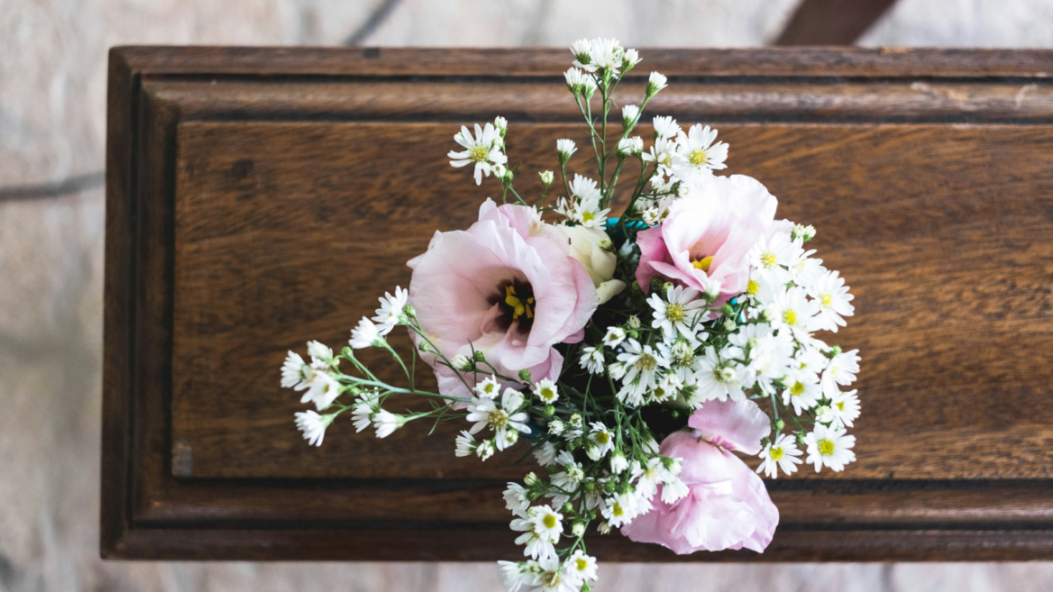 zarter blumenstrauß mit margeriten auf holztablett