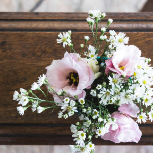 zarter blumenstrauß mit margeriten auf holztablett