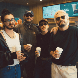 cuatro amigos con café en cafetería moderna