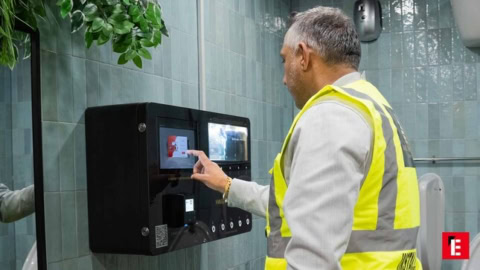 man using wall mounted touchscreen in high vis vest