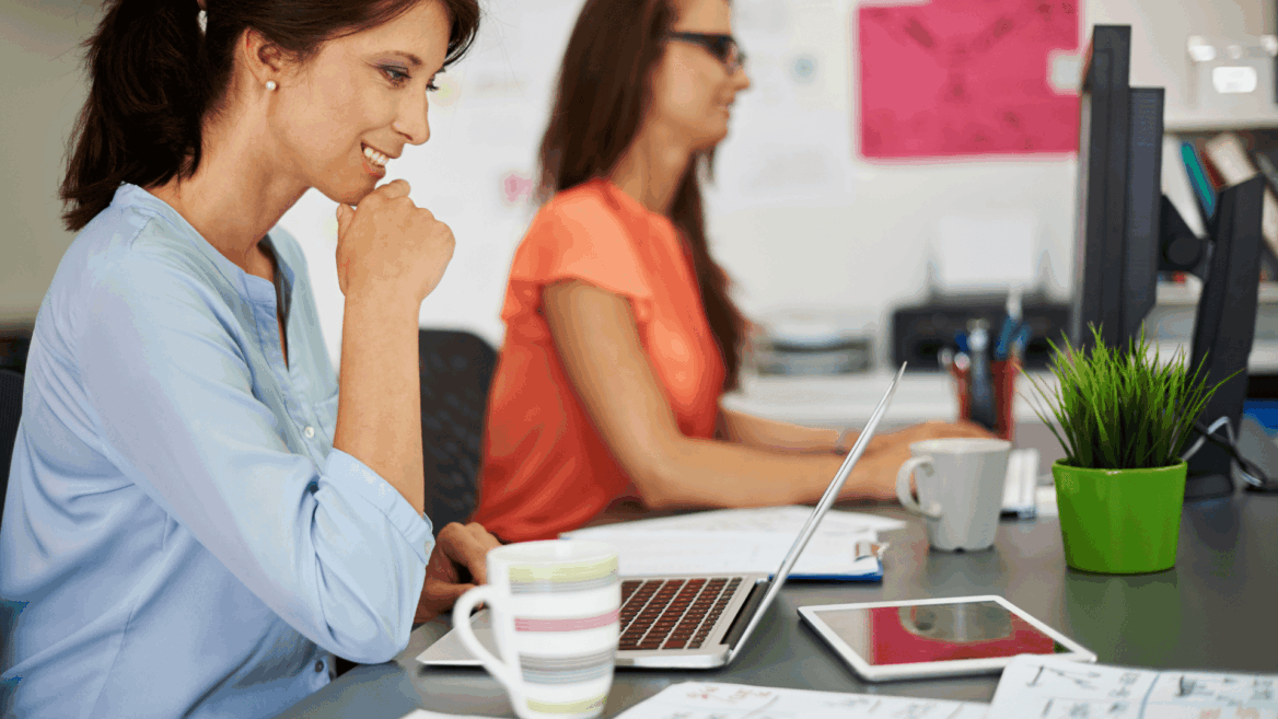 mujeres en oficina colaborando con ordenador