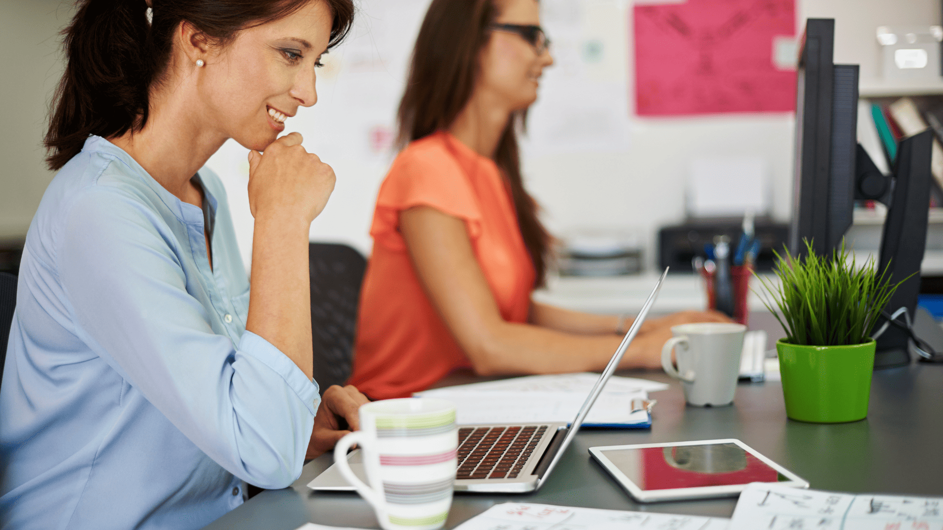 mujeres en oficina colaborando con ordenador