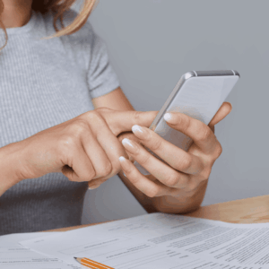 mujer concentrada con móvil, documentos y portátil