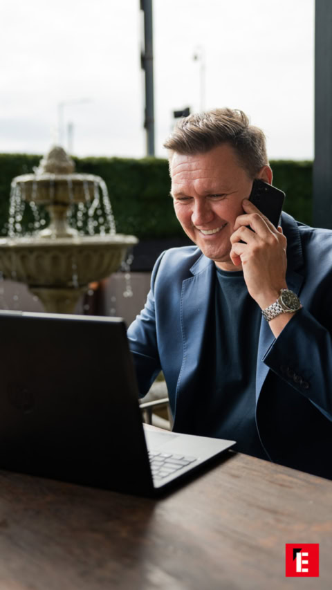 smiling businessman on phone with laptop outdoors