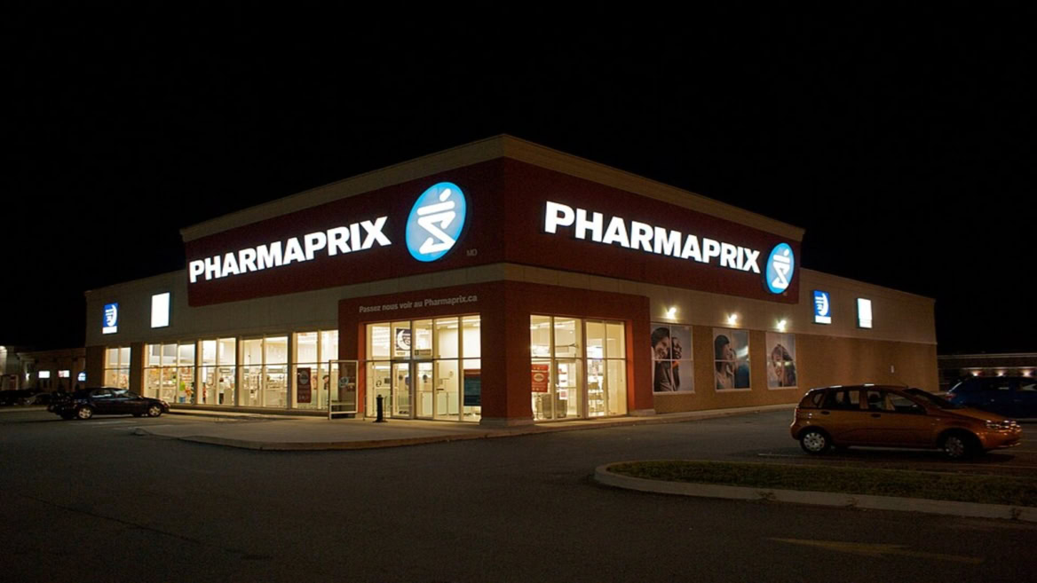 pharmaprix illuminé de nuit, façade et parking vide