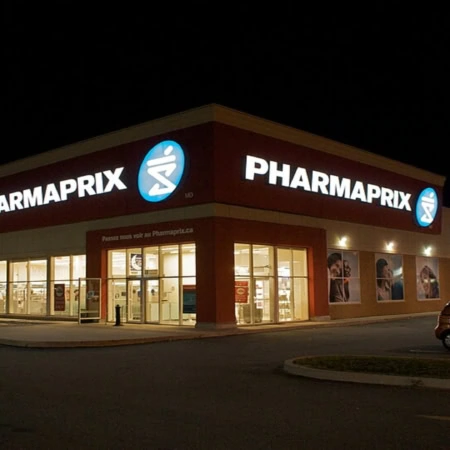 pharmaprix illuminé de nuit, façade et parking vide