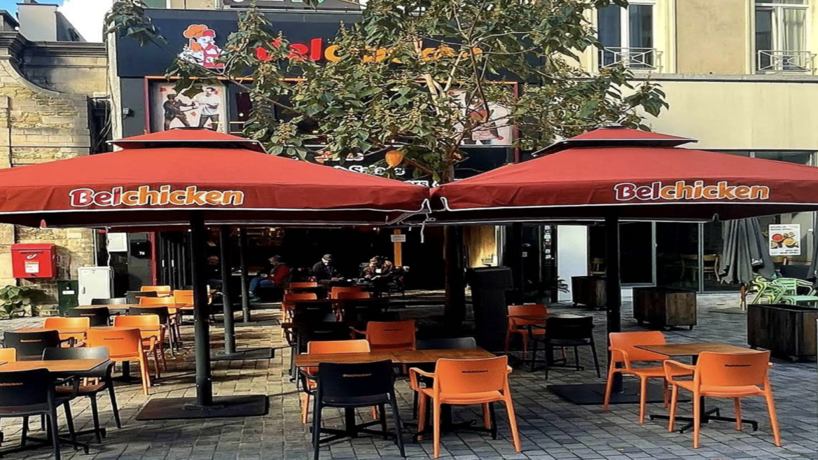terrasse belchicken avec parasols rouges et tables dehors