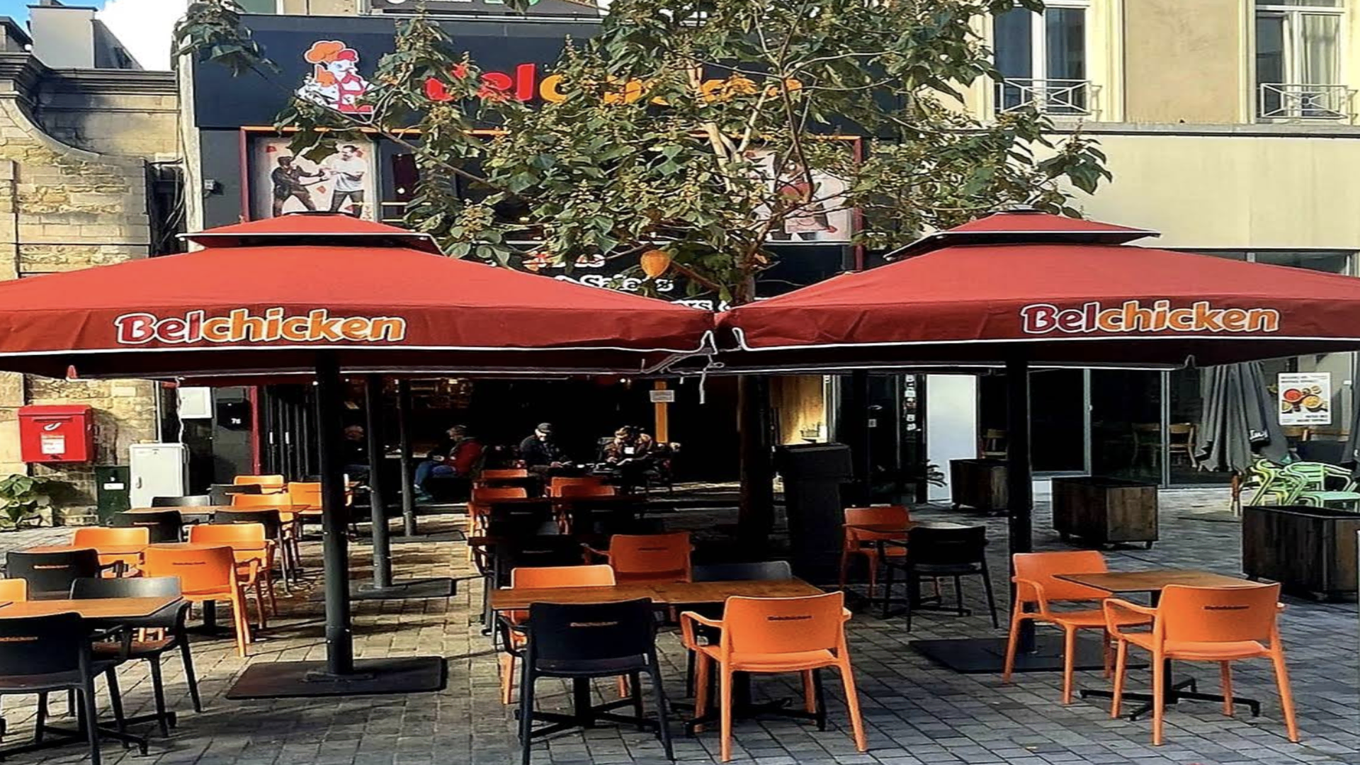 terrasse belchicken avec parasols rouges et tables dehors
