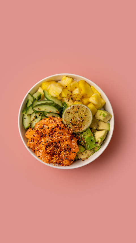 bowl poké saumon, avocat et ananas sur fond rose