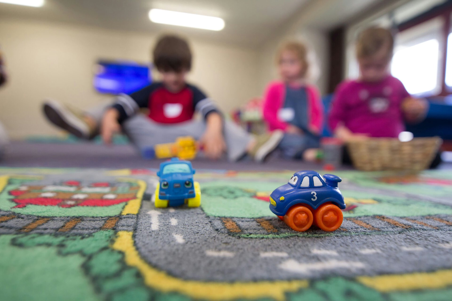 macchinine giocattolo sul tappeto stradale, bambini sullo sfondo