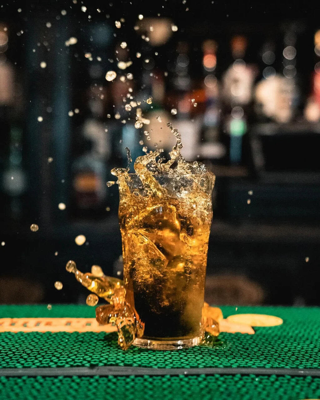 cocktail ambré en éclaboussure sur bar vert
