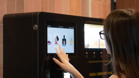 woman selecting fragrance on touchscreen kiosk