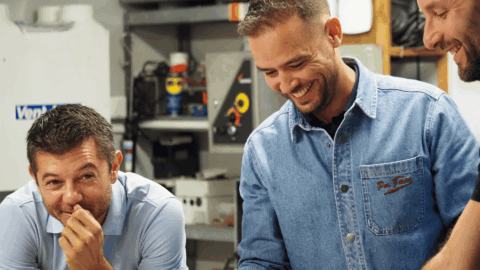 trois ouvriers souriants dans un atelier mécanique