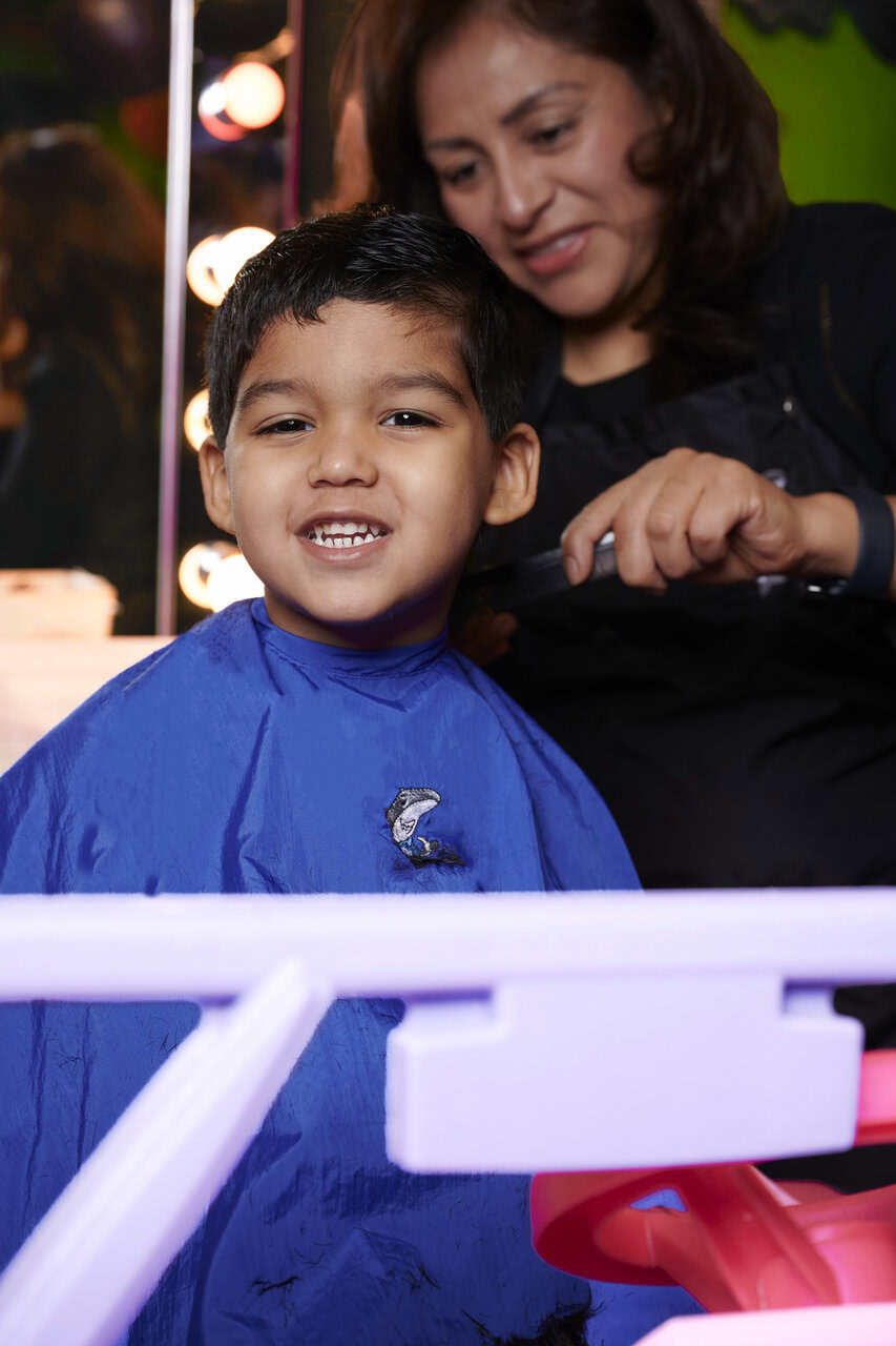 niño sonriente durante corte de cabello en salón