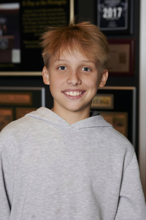 retrato sonriente de niño con sudadera gris