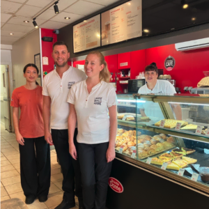Équipe de café devant vitrine de pâtisseries