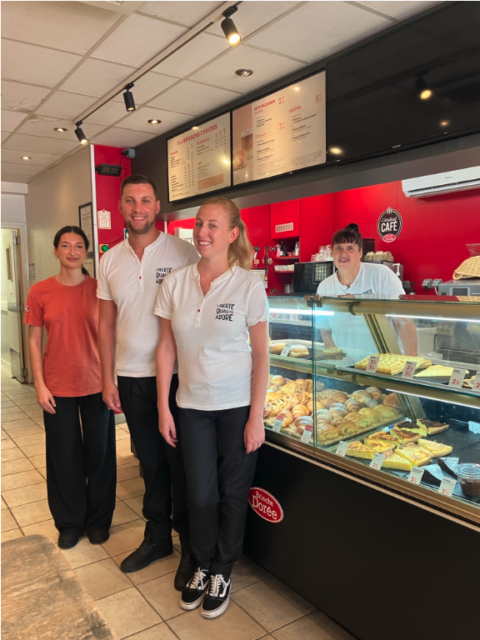 Équipe de café devant vitrine de pâtisseries