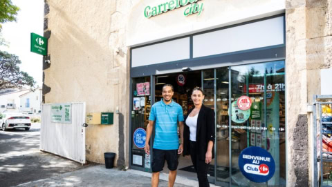 entrée carrefour city avec deux personnes sour iantes