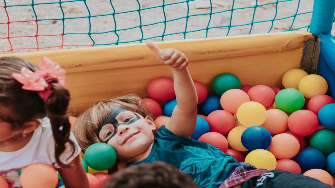 child smiling in colourful ball pit