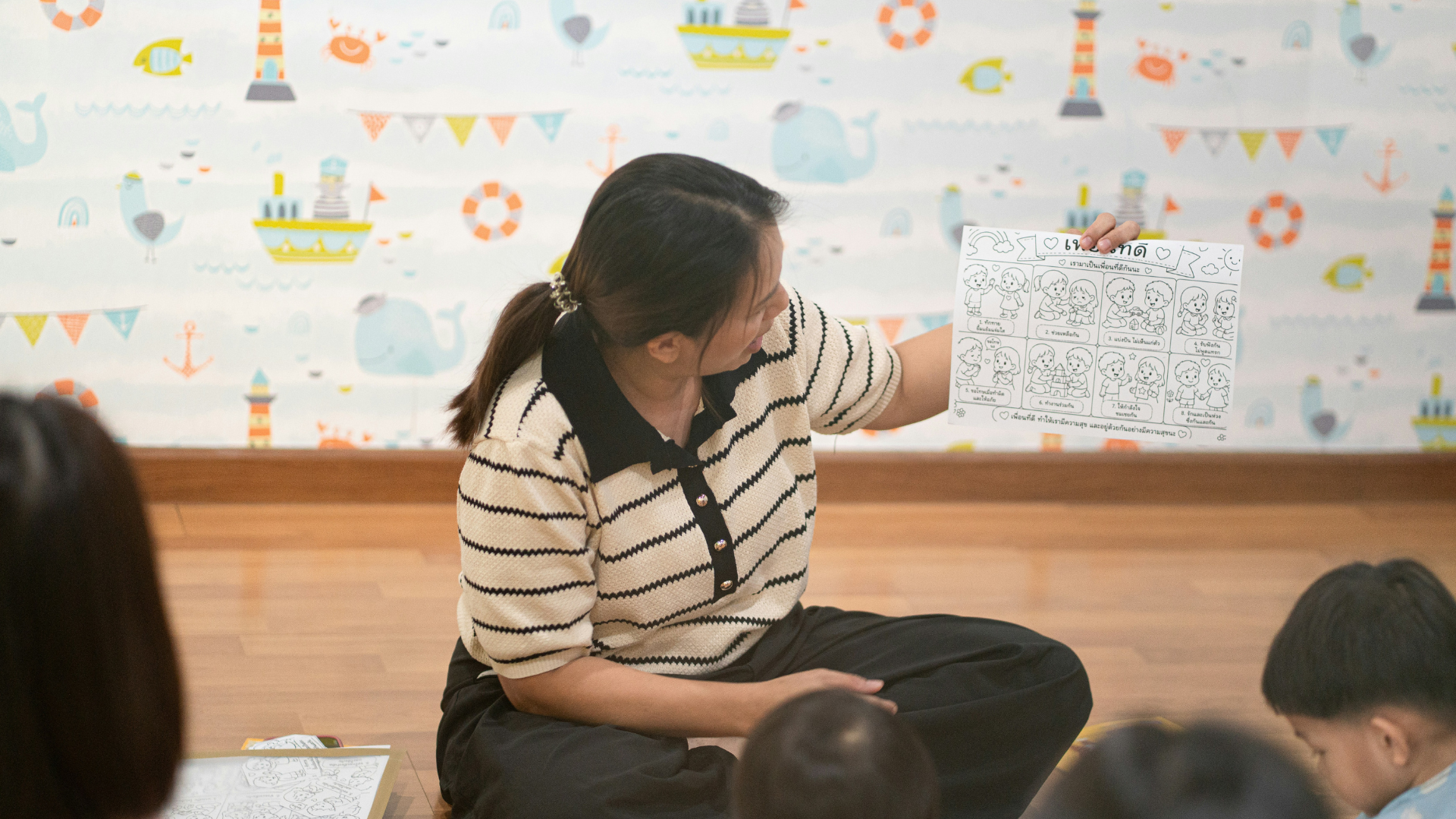 teacher reading worksheet to children in classroom