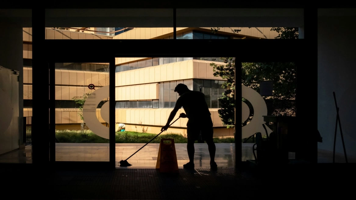 silhouette cleaner mopping glass entrance, modern courtyard