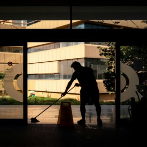 silhouette cleaner mopping glass entrance, modern courtyard