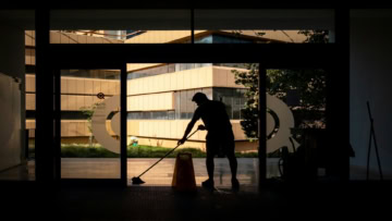 silhouette cleaner mopping glass entrance, modern courtyard