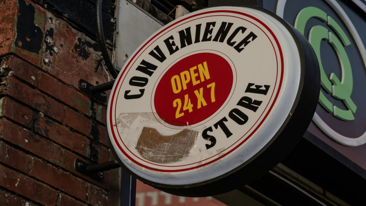convenience store sign open 24/7 on brick wall